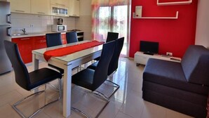 A compact living space with a dining area, kitchenette, and a seating area with a TV.