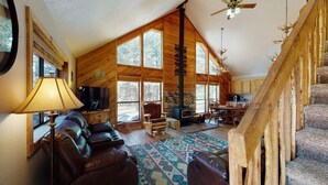 A spacious living room with a fireplace, leather sofa, and a large window.