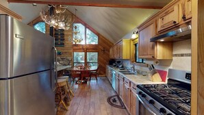 A spacious kitchen with wooden cabinets, a stainless steel refrigerator, a gas stove, and a dining area with a wooden table and chairs.