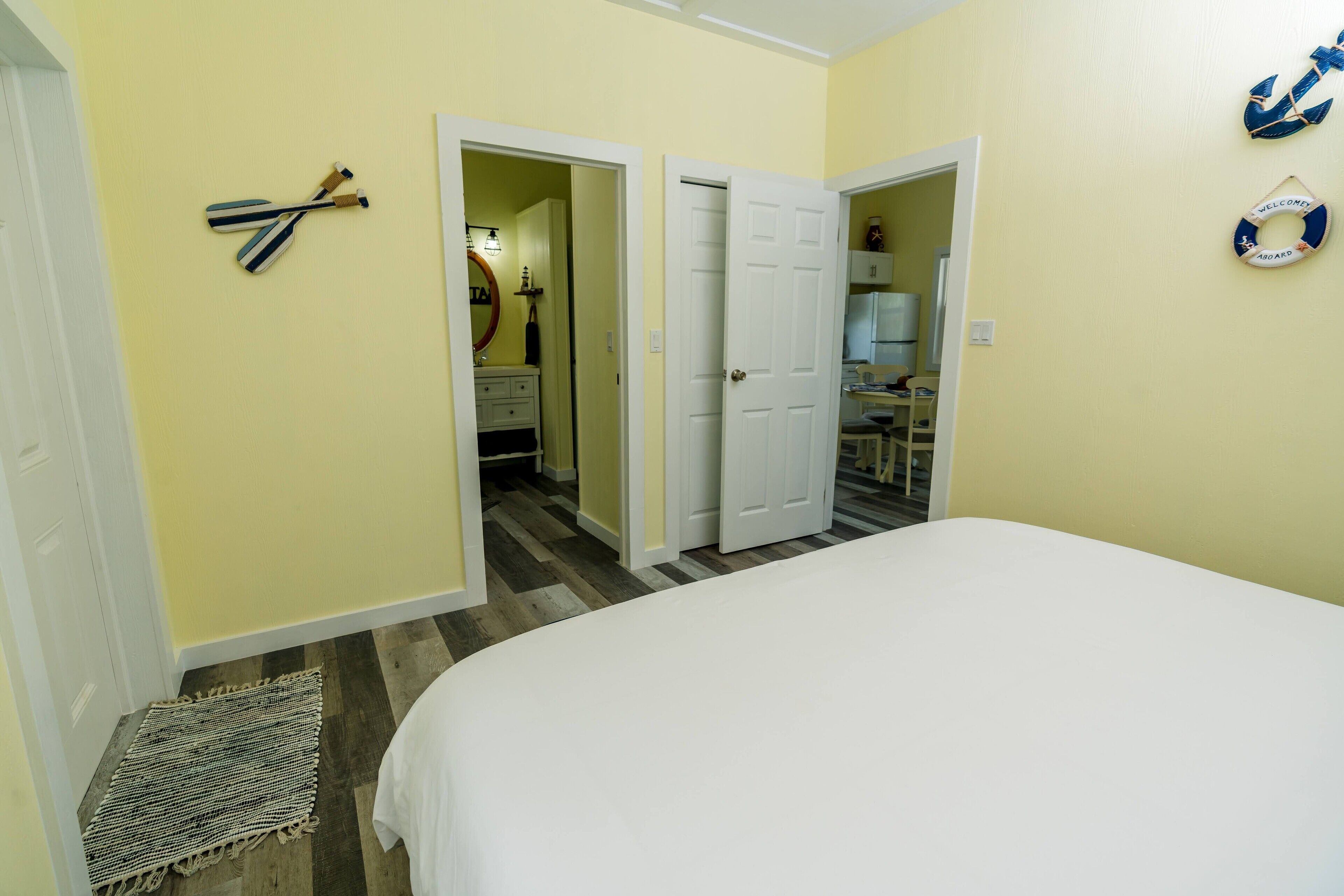 A bedroom with a bed, a door leading to a bathroom, and a wall with a life ring decoration.