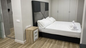 Ett modernt sovrum med en säng, sängbord och en garderob.