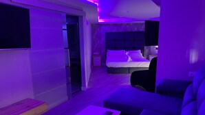 A modern living room with a sofa, a coffee table, and a bed with a headboard. - Luxury Gold (Linares)