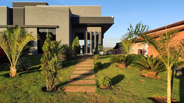 A modern building with a flat roof, large windows, and a paved pathway leading to the entrance.