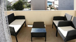 A balcony with two black wicker sofas and a small table, overlooking a residential area with houses and a body of water. - Remarkable 2-bed Apartment in Srima With sea View (Vodice)