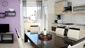 A modern kitchen with a dining area, a TV, and a view through a glass door. - Remarkable 2-bed Apartment in Srima With sea View (Vodice)