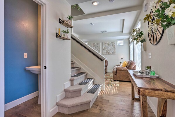 Staircase leads to an upper level, with a dining table and decorative art piece.