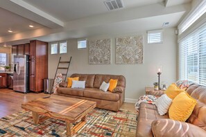 Relax in this stylish living area with a modern kitchen, featuring a comfortable sofa, coffee table, and vibrant rug.