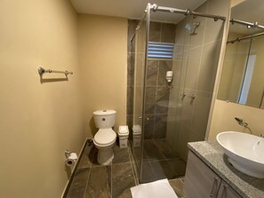 Une salle de bain moderne équipée de toilettes, d’une douche et d’un lavabo.