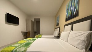 Une chambre d’hôtel avec deux lits, un bureau, une chaise et des œuvres d’art accrochées aux murs.