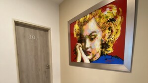 Un couloir avec une porte en bois portant le numéro « 202 » et une grande peinture abstraite accrochée au mur.