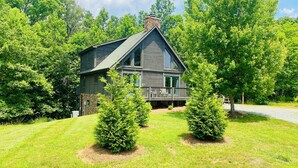 A log cabin with a porch, surrounded by a well-maintained lawn and trees. - The Rocking A Frame - modern meets cozy. (Danbury)