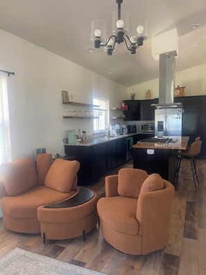 A modern kitchen with a central island, dark cabinetry, and a chandelier.