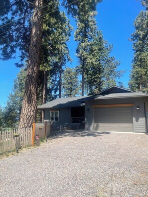 A residential property with a garage, a gravel driveway, and a wooden fence.