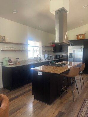 A modern kitchen with a central island, black cabinetry, stainless steel appliances, and a window providing natural light.