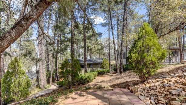 Un sendero pavimentado que atraviesa una zona boscosa, con una casa al fondo.