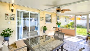 Ein Patio mit Glastisch und -stühlen, Blumentöpfen und einem Deckenventilator.