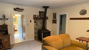 A living room with a stone fireplace, a sofa, a wooden side table, and a lamp.