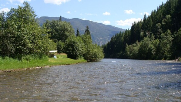 A river with a small bridge, surrounded by dense forest and mountains in the background. - THE CABIN on Lake Creek River (Troy)