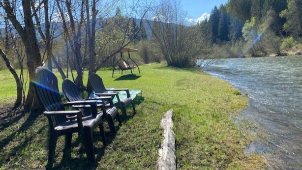 A riverside picnic area with chairs and a swing set.