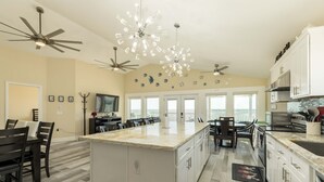 A spacious kitchen with a large island, white cabinetry, and modern lighting fixtures. - Galveston Bay Views & Pier! San Leon Gulf Getaway (San Leon)