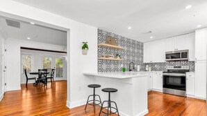 Una cocina moderna con armarios blancos, un salpicadero blanco y negro y una isla central con taburetes.