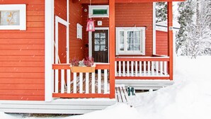 Una casa de madera roja con un porche blanco y un buzón verde.