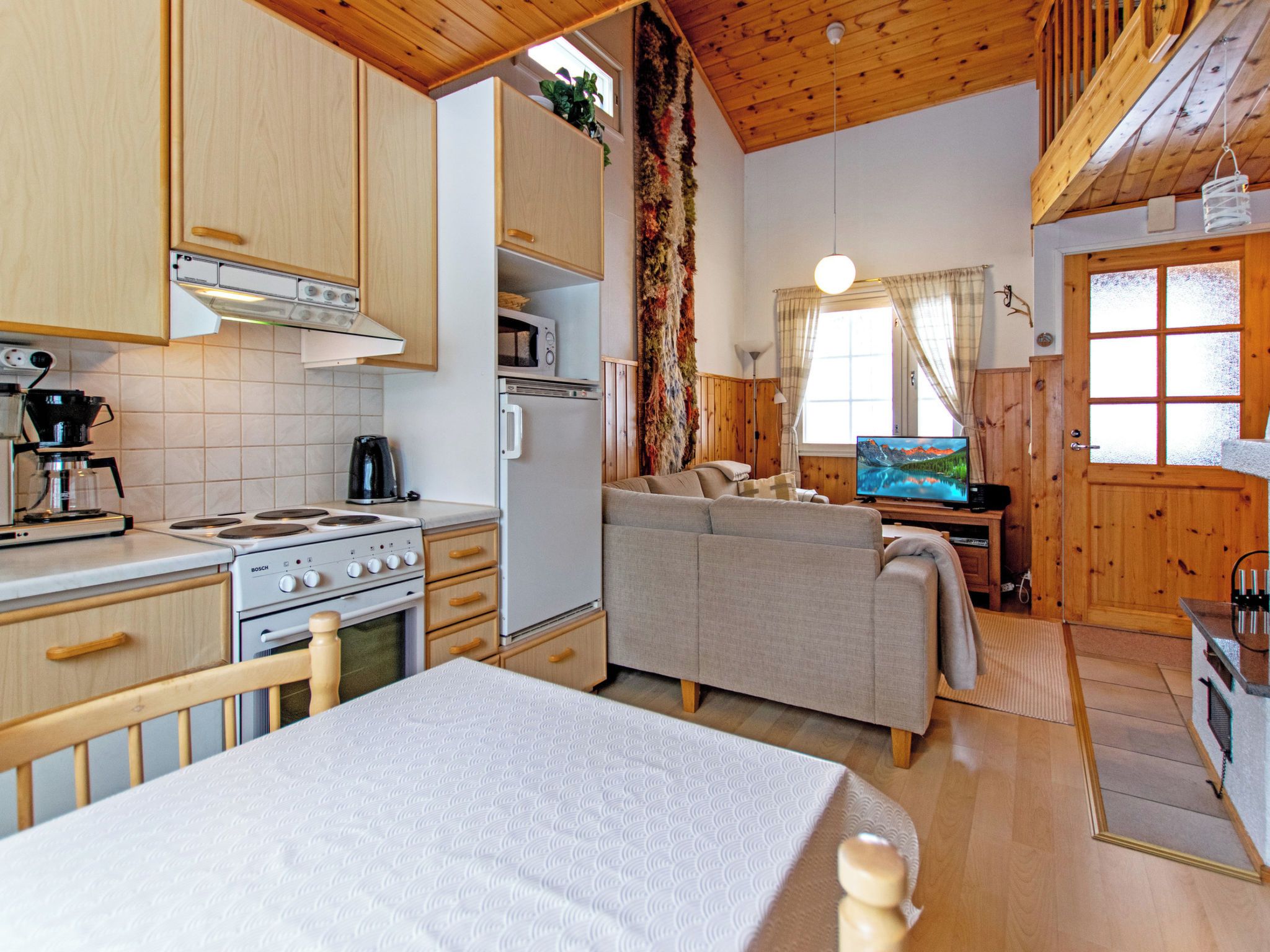 A compact living space with a kitchenette, a sofa, a television, and a bed.
