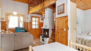 Un interior acogedor de cabaña con sala de estar, chimenea, habitación de altillo y comedor.