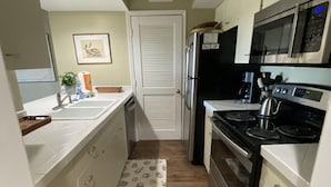 A compact kitchen with white cabinets, a stainless steel refrigerator, a microwave, and a stove. - Beautiful Sunsets--Beachfront, Club Amenity Cards included with price! (Seabrook Island)
