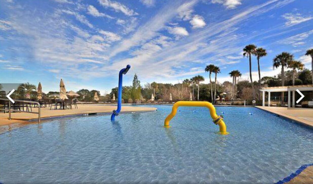 Una piscina con agua azul cristalina, rodeada de palmeras y un cielo despejado.