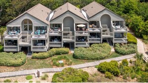 A multi-story house with balconies, a wooden deck, and a landscaped garden. - Beautiful Sunsets--Beachfront, Club Amenity Cards included with price! (Seabrook Island)