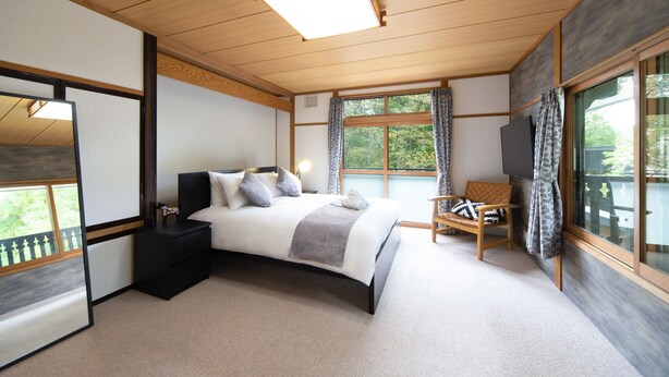 Une chambre moderne avec un grand lit, une télévision et une vue sur l’extérieur.