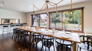 Un espace repas avec une longue table dressée pour six personnes, entourée de chaises noires.