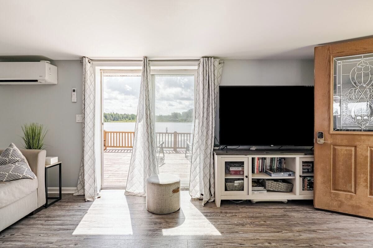 Een woonkamer met een televisie, een bank, een salontafel en uitzicht op een balkon.