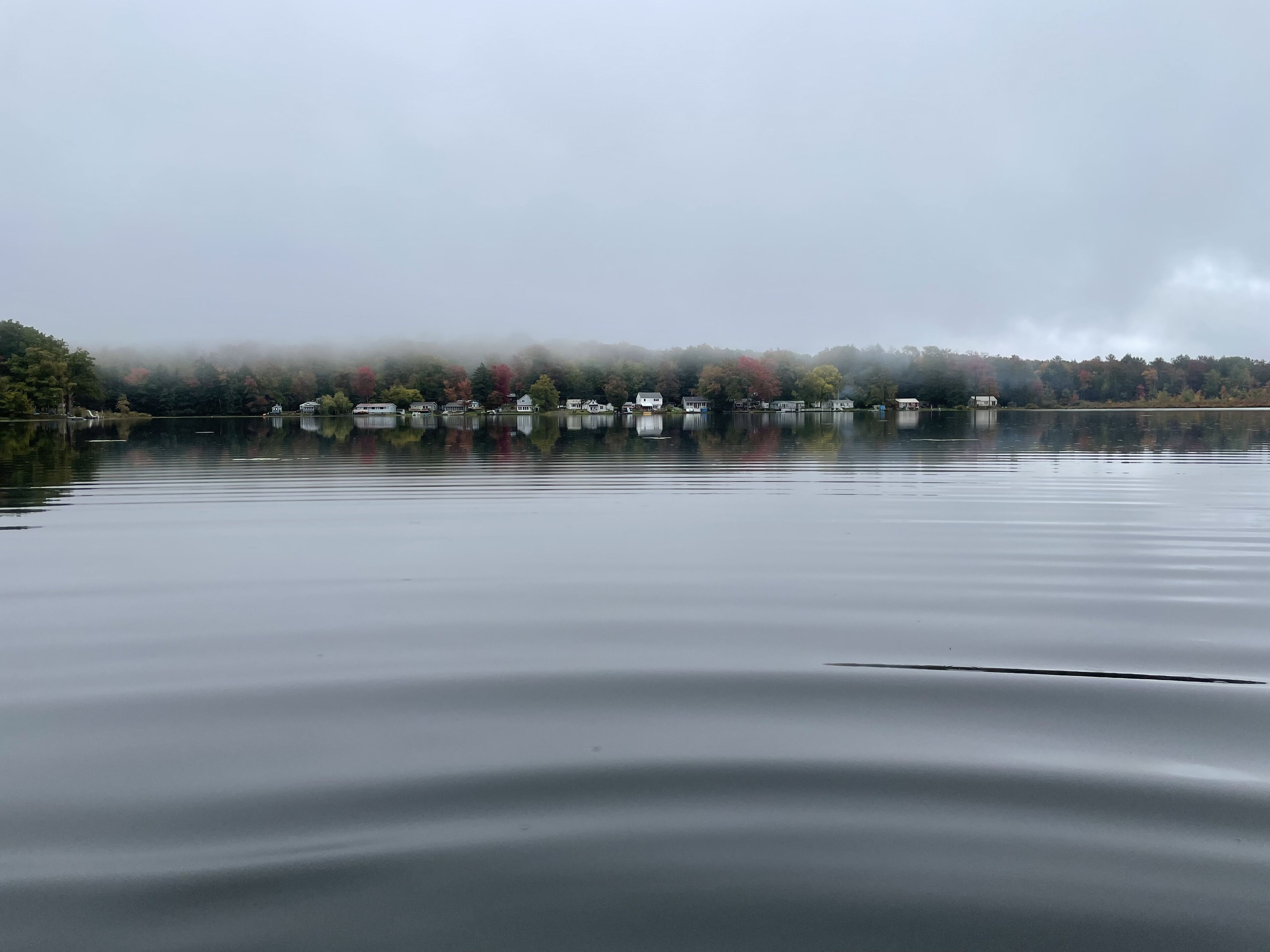 Un lac paisible où se reflètent les maisons sur la surface de l’eau.