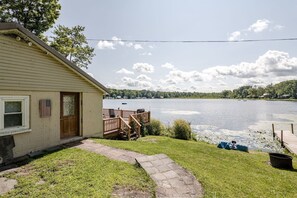 A house with a deck overlooking a lake, a pathway leading to the door, and a small boat docked near the water. - ✨ Lakeside Reflections (Oxford)
