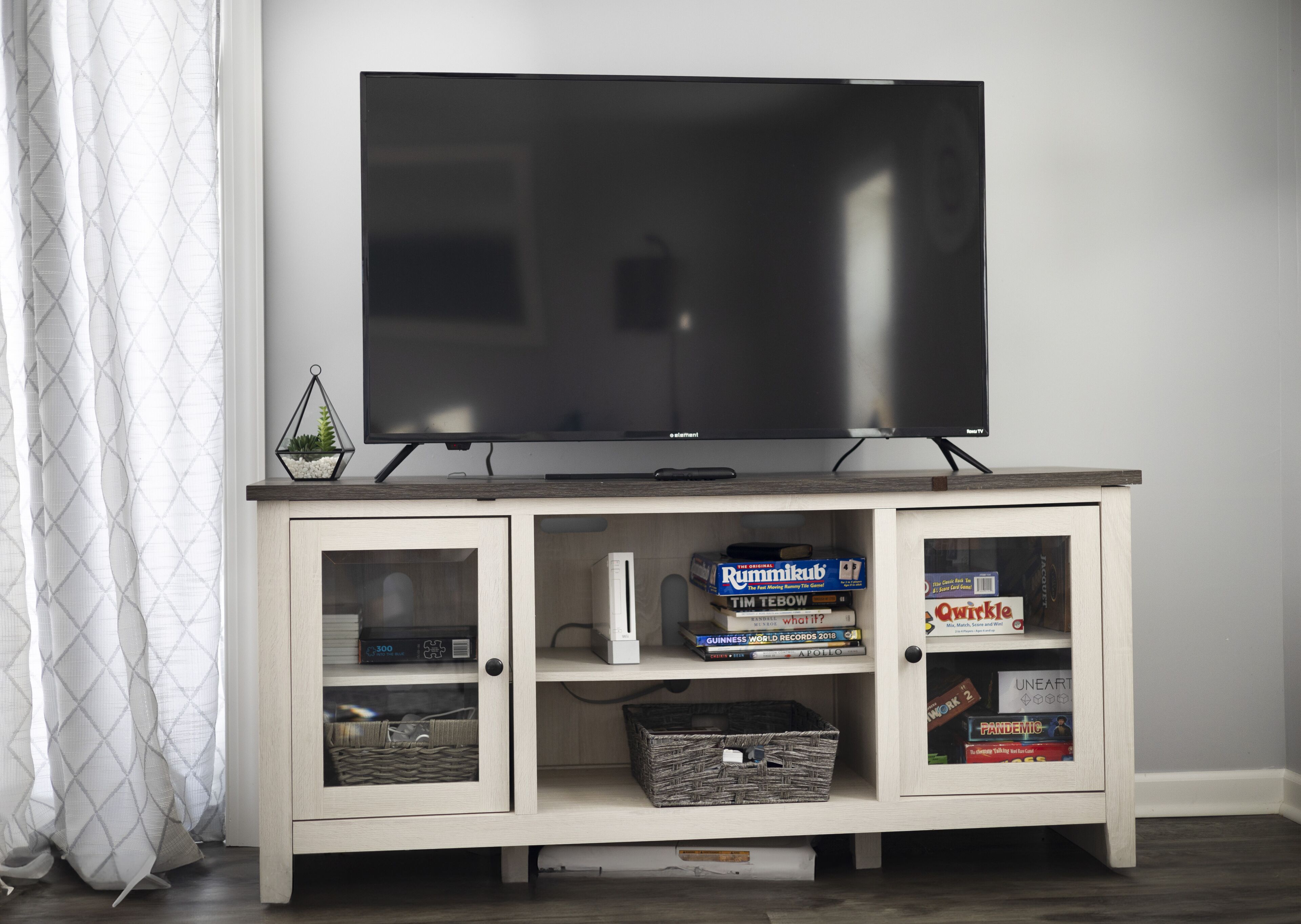 Un téléviseur posé sur un meuble en bois, avec des étagères en dessous.