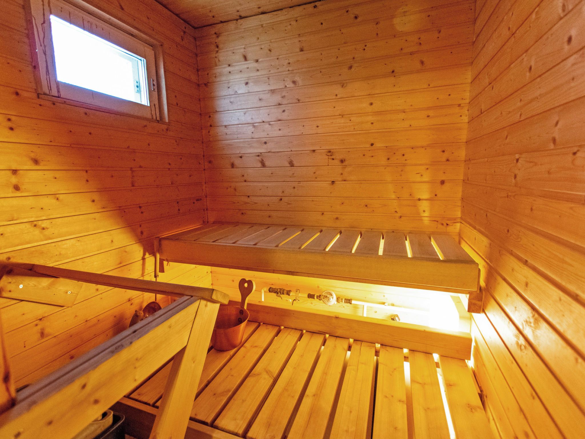 Interno di una baita in legno con un letto a castello, una finestra e un tavolino con un oggetto a forma di cuore.