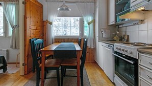 A compact kitchen with wooden cabinets, a stove, and a dining area with a table and chairs.