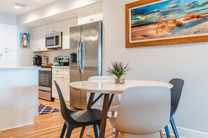 A modern kitchen with white cabinets, stainless steel appliances, and a dining area with a round table and chairs.