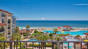 A resort with multiple swimming pools, a beach, and a view of the ocean.