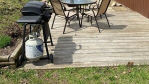 Een terras met buitenmeubilair, een barbecue en een propaantank.