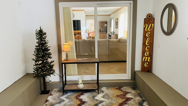 Een moderne entree met een kerstboom, een welkomstbord en een spiegel aan de muur.