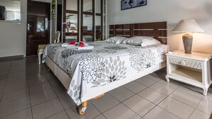 A neatly arranged hotel room with a bed, a nightstand, a lamp, and a large mirror.