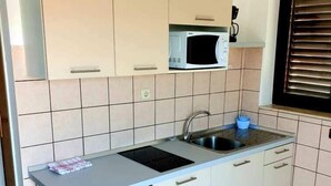 A compact kitchen with a microwave, sink, and a small refrigerator. - Lovely 1-Bed Apartment with sea view in Srima (Srima)