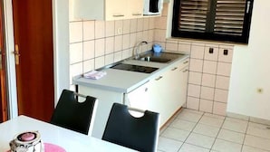 A compact kitchen with white cabinets, a microwave, a sink, and a window with blinds. - Lovely 1-Bed Apartment with sea view in Srima (Srima)