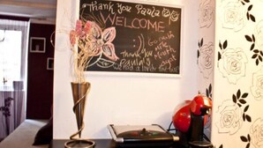 A welcome sign with a floral design, a blackboard, a red lamp, and a decorative vase on a table. - Apartment in center Old town (Dubrovnik)
