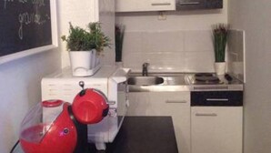 A modern kitchen with white cabinets, a stainless steel sink, and a red kettle on the counter. - Apartment in center Old town (Dubrovnik)