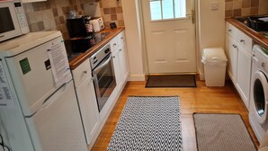Eine kleine Küche mit Mikrowelle, Toaster, Backofen und Waschmaschine.