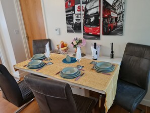 Une table à manger dressée avec des assiettes, des verres et des couverts, entourée de chaises en cuir.